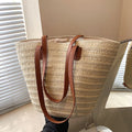 Bolsa trançada de palha bege com alça de couro da Loja Morela, ideal para looks de verão e estilo casual.