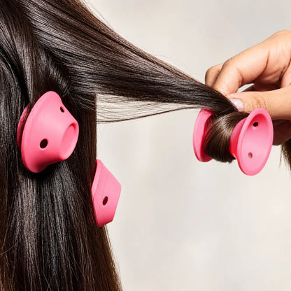 Mão enrolando uma mecha de cabelo castanho em um modelador de silicone rosa.