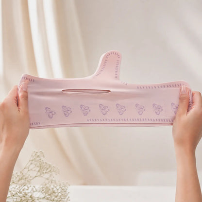 Detalhe da elasticidade e flexibilidade do tecido rosa da máscara modeladora facial V-Line sendo estendido com as mãos Loja Morela