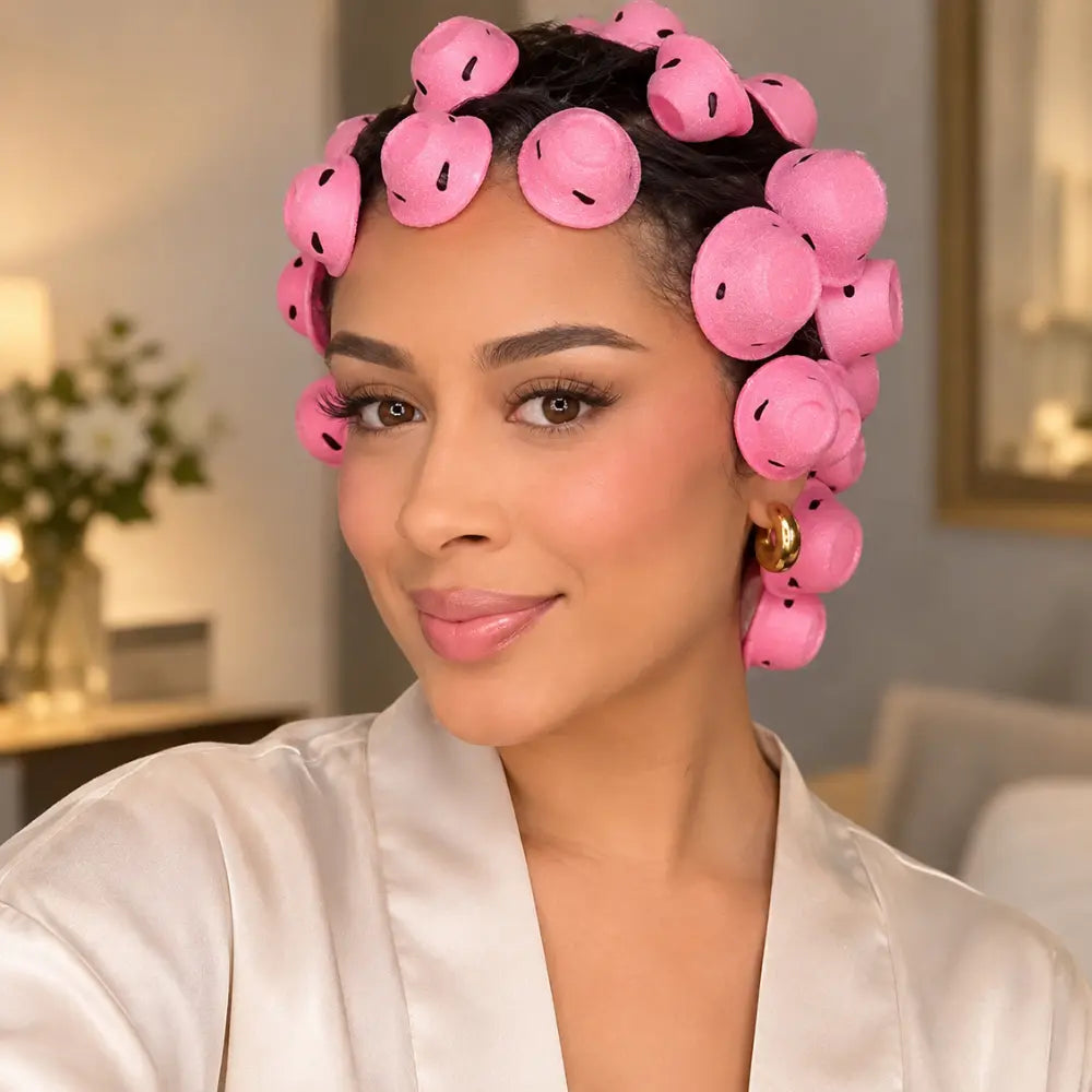 Mulher com os modeladores rosa presos na cabeça aguardando a secagem dos fios.