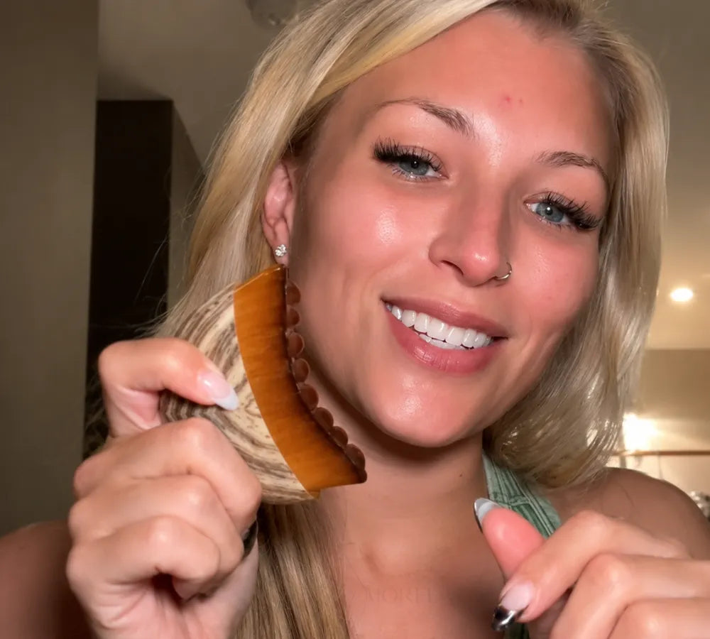 Mulher sorrindo e segurando a escova massageadora facial após o uso Loja Morela